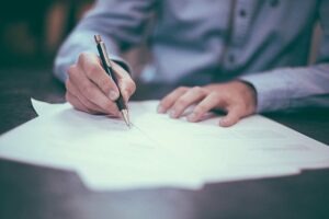 person signing lease agreements on a table