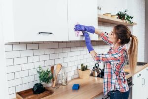 person cleaning the kitchen cabinets