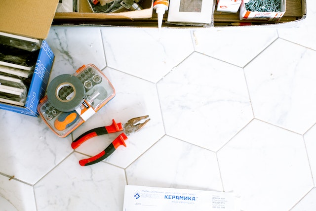 A box of tools and a pair of pliers on a marble floor