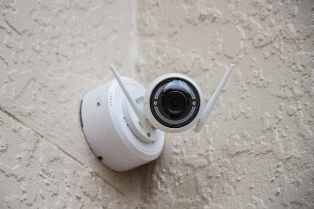 White security camera in the corner of a beige wall