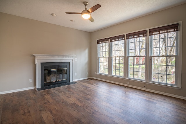 Wide shot of an empty room with wooden floors, beige walls, a black fireplace, and wide windows