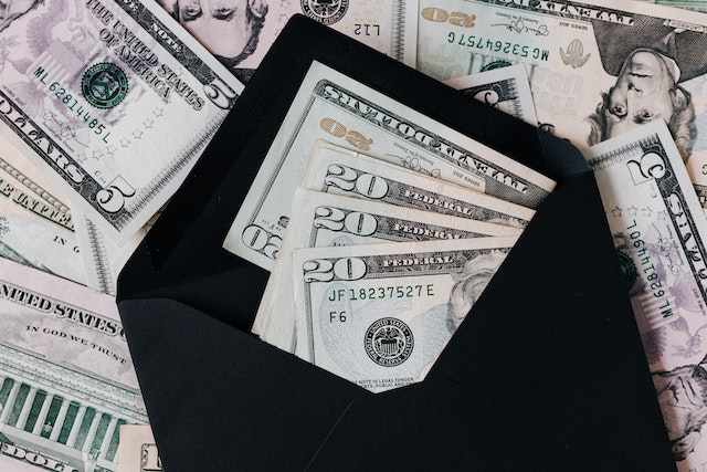 Open black envelope filled with U.S. dollar bills