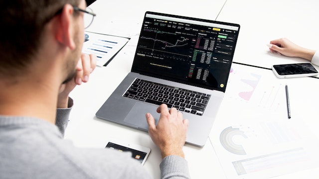 Person in gray long-sleeve looking at graphs on their silver laptop