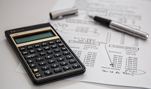Black financial calculator on top of a printed paper, next to an uncapped silver pen