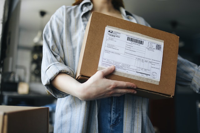 Person holding a brown package with a USPS label on it