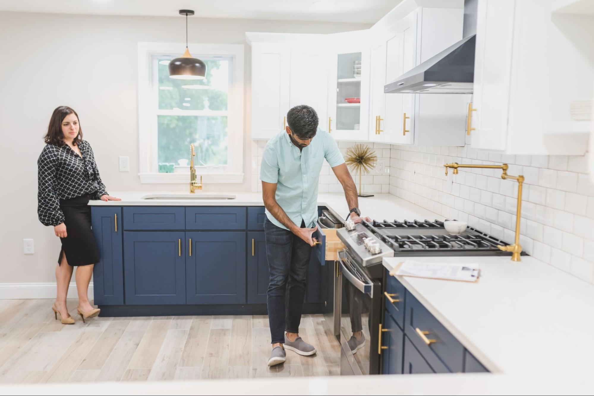 Two people inspecting a bright-lit kitchen