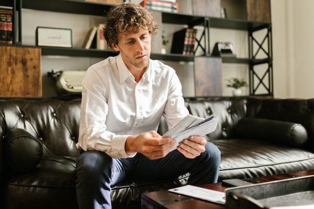 Person sitting on a black couch and going through the mail