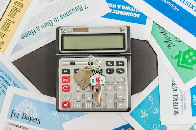 real-estate-articles-surrounding-a-calculator-with-house-keys-on-it-with-a-house-keychain-attached