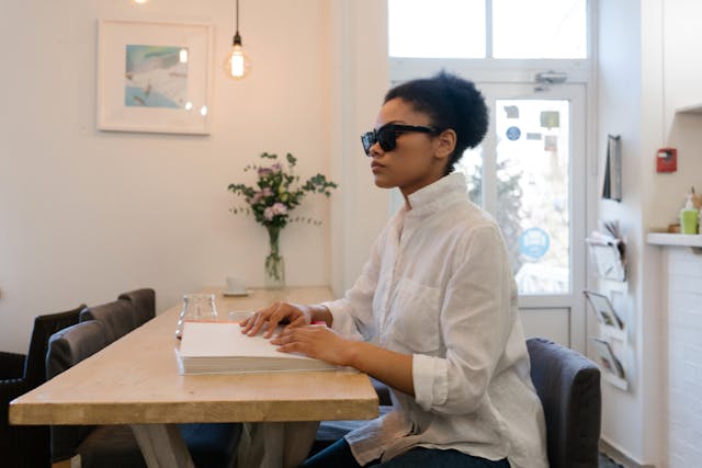 blind-person-sitting-at-a-table-reading-a-braille-book