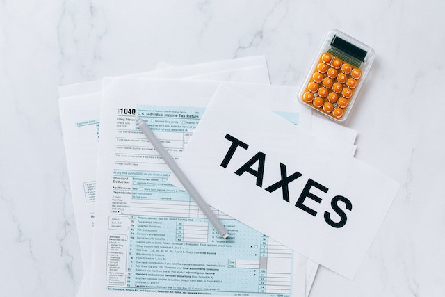 stack-of-tax-forms-and-a-calculator-on-a-white-table