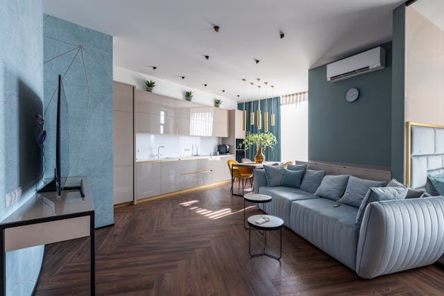 modern-open-concept-living-space-with-a-sleek-kitchen-light-blue-sofa-wooden-floors-and-minimalist-decor