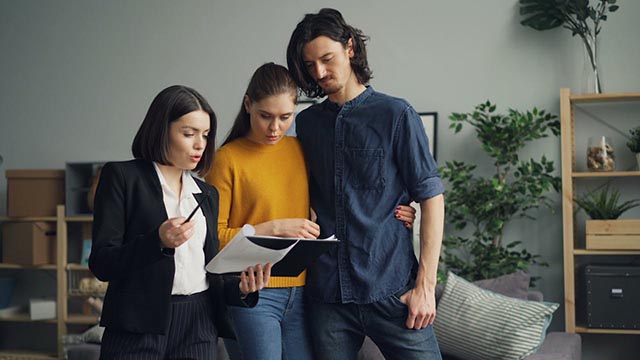 professional-explaining-documents-to-a-couple-inside-a-modern-staged-living-room